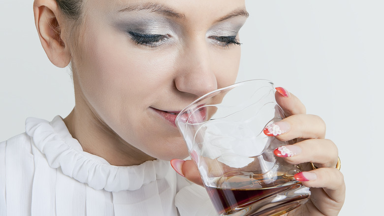 woman sniffs a glass of whiskey