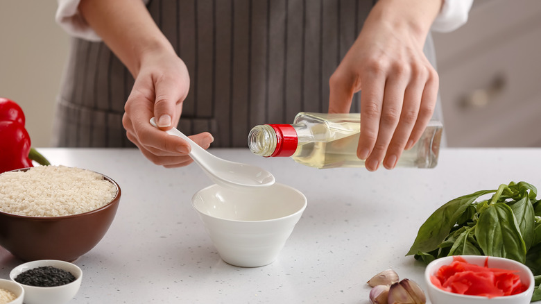 Woman pouring tablespoon of vinegar