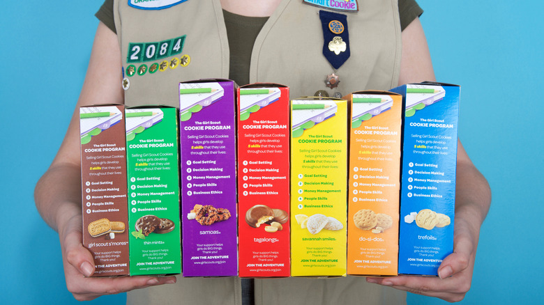 Girl Scout holding colorful boxes of cookies