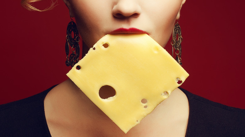 person with slice of cheese in mouth