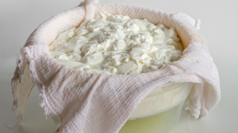 curds and whey being separated in a bowl