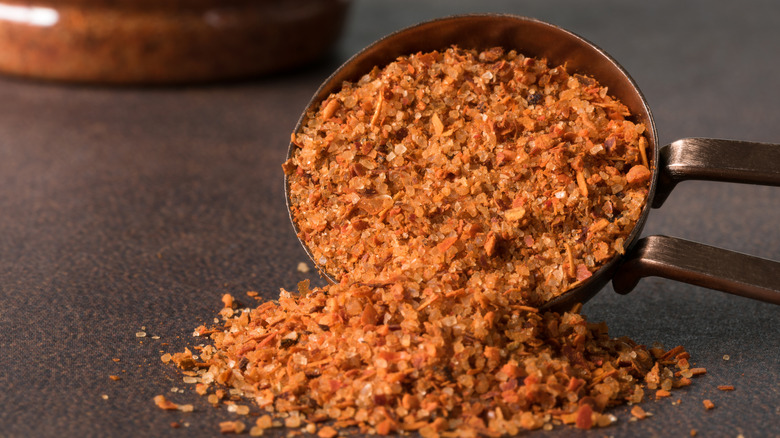 Tajín poured from a spoon partially onto dark surface