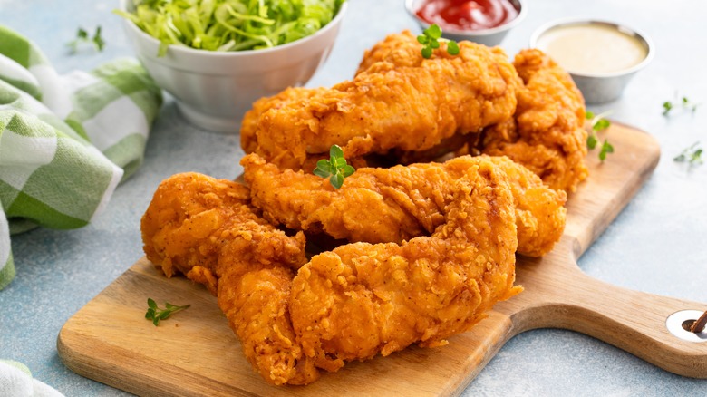 Chicken tenders on cutting board with dipping sauces