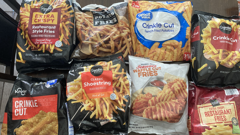 8 bags of store-brand frozen french fries sit out on a table.