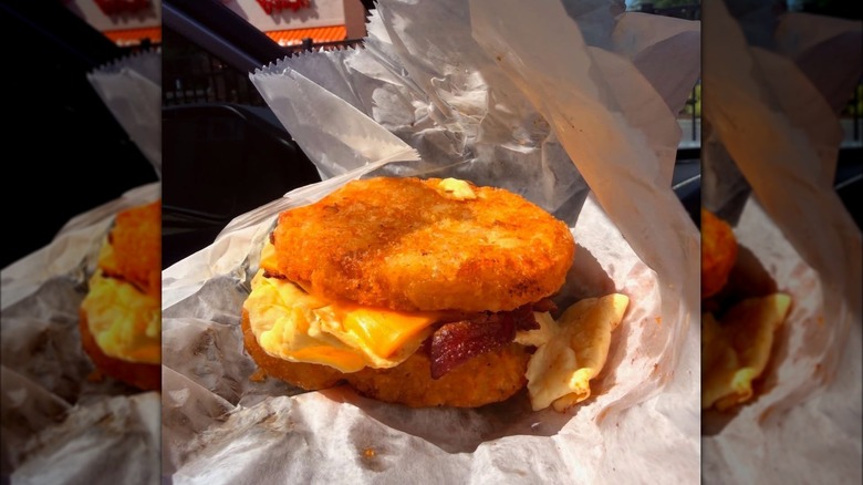Person holding a Carolina Crunch sandwich from Bojangles in paper wrapper.