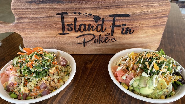 Island Fin Poke logo cutting board behind two poke bowls