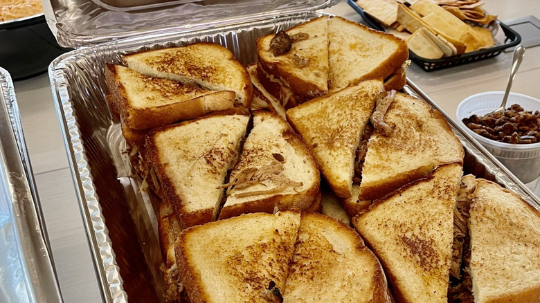 Six grilled cheese sandwiches split in half, on an aluminum tray
