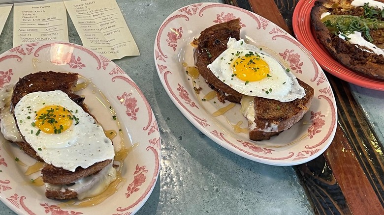 Two plates of grilled cheese topped with one fried egg each
