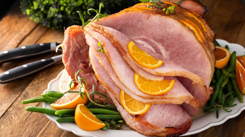 Spiral sliced ham with orange slices on table