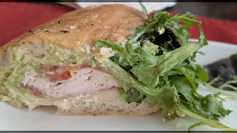 A halved Italian sub on a crusty roll filled with sliced turkey, cheese, shredded lettuce, and tomato