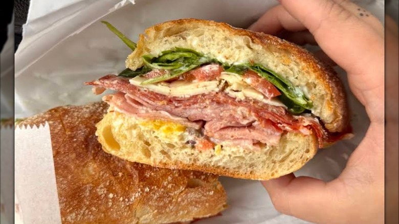 An Italian sub with layers of deli meats, cheese, lettuce, and oil on a crusty roll