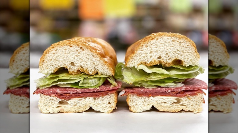 An Italian sub cut in half, showing layers of deli meats, cheese, and lettuce