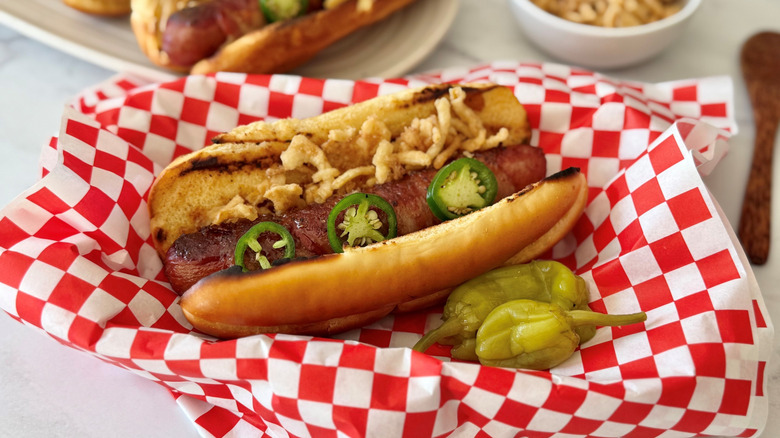 Bacon-wrapped hot dog with jalapeño and crispy onions in serving basket