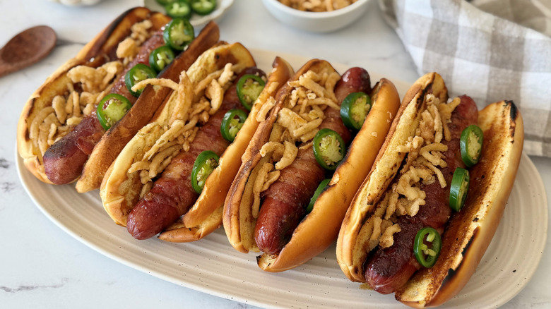 Bacon wrapped hot dogs topped with jalapeños and crispy onions