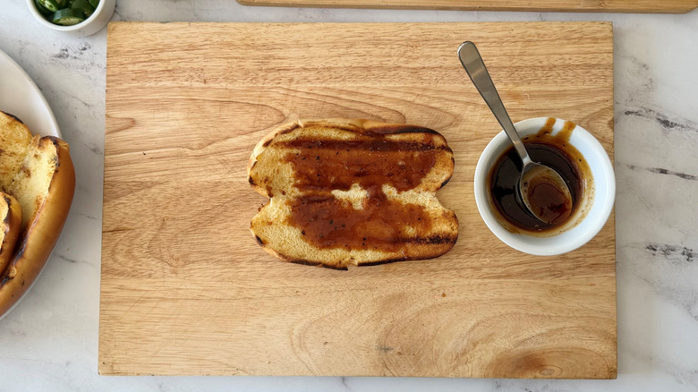 Hot dog bun topped with sauce next to small bowl of sauce
