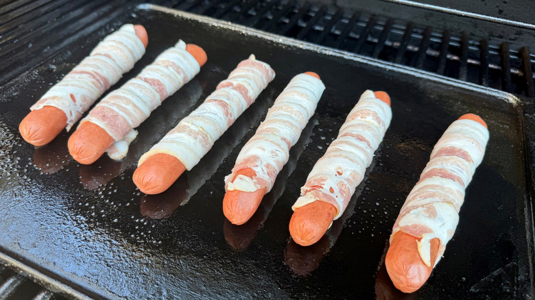 Bacon-wrapped hot dogs on grill skillet