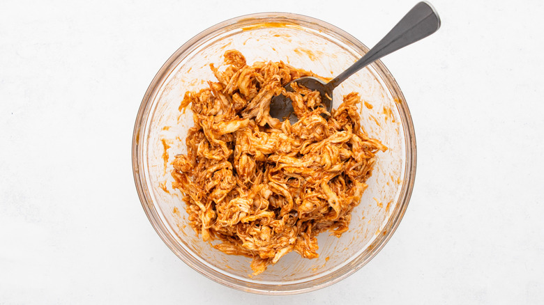 BBQ shredded chicken in glass bowl with spoon