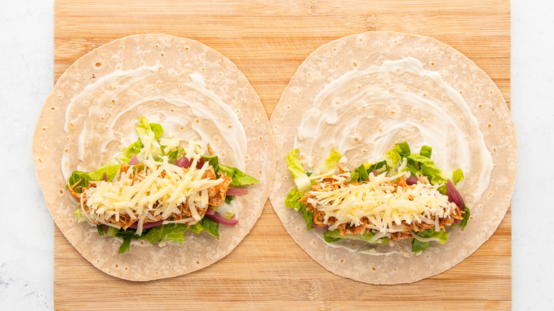 Two flour tortillas topped with BBQ chicken, shredded cheddar, and salad