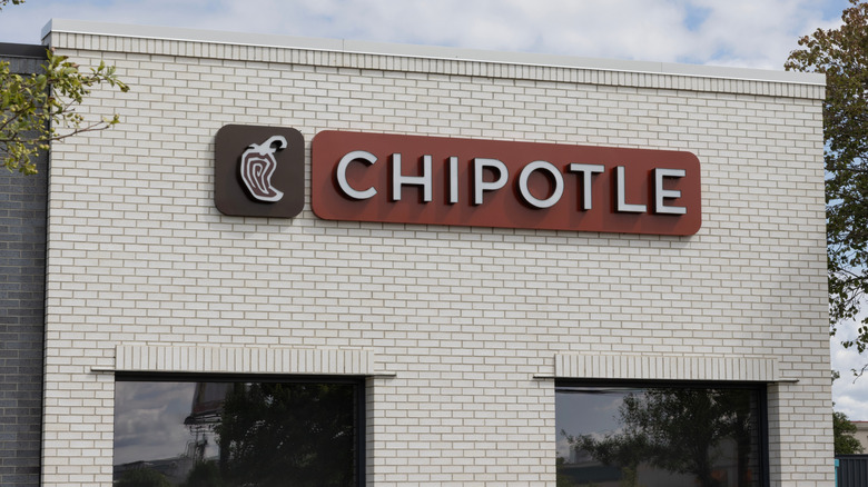 A white brick Chipotle building with a brown sign
