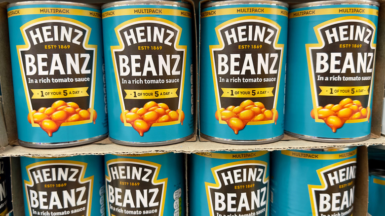 Bright blue cans of Heinz Beanz on cardboard shelf.