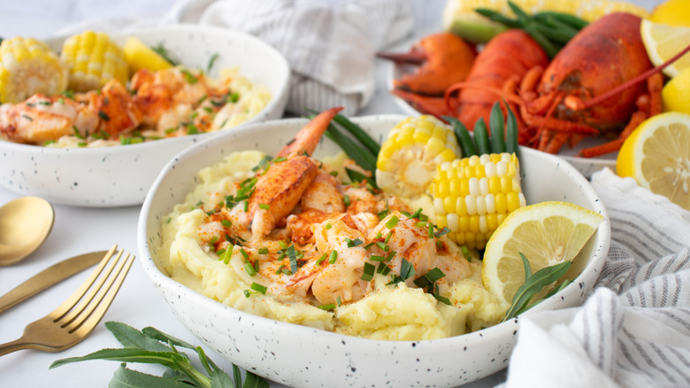 two bowls of lobster mashed potatoes with beurre bier blanc sauce next to plate of lobsters