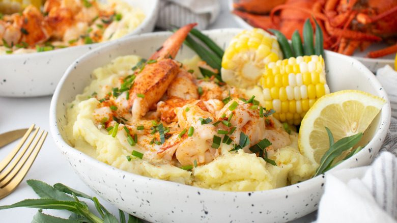 bowl with lobster mashed potatoes, beurre bier blanc sauce, corn, and lemon wedges