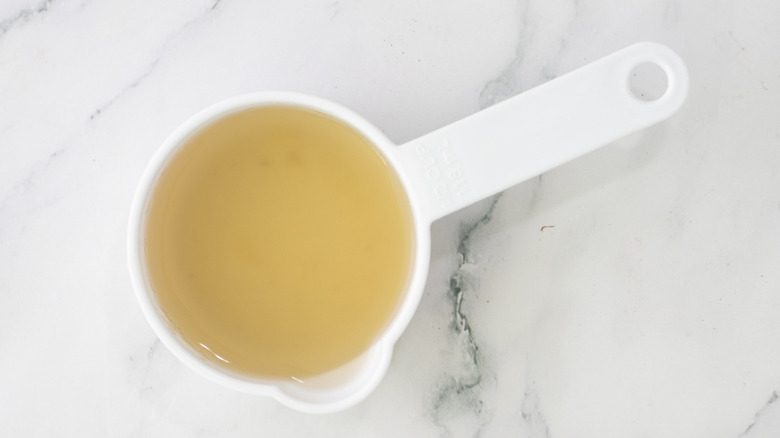 broth in measuring cup on marble surface