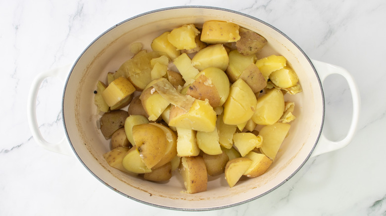 cooked potato chunks in pot on marble surface
