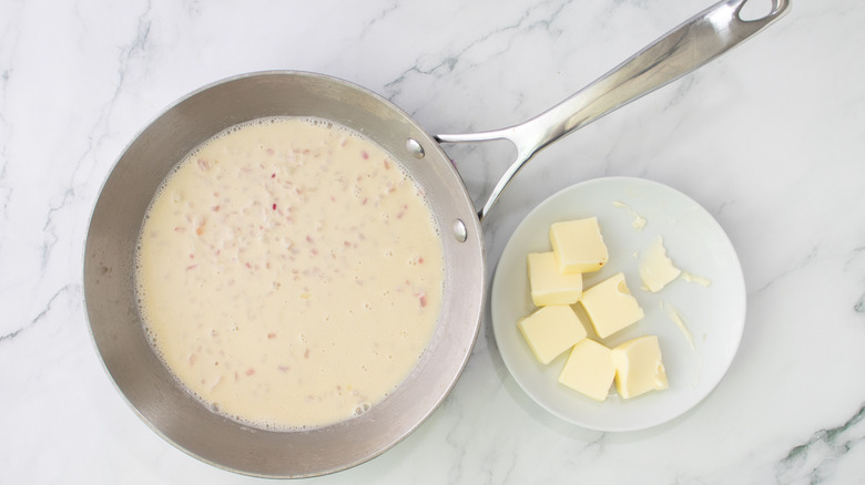 beer and cream sauce in skillet next to plate of cubed butter