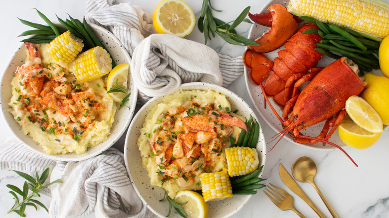 two bowls of lobster mashed potatoes, corn, and beurre bier blanc sauce next to plate of lobster, corn, and lemon