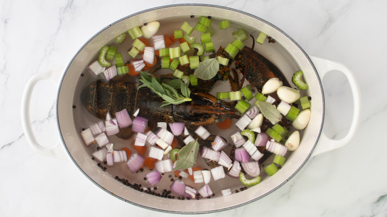 pot with water, raw lobster, vegetables, and seasonings