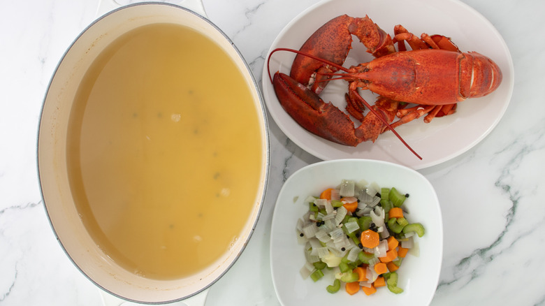 aerial view of pot with broth and plates with lobster and veggies