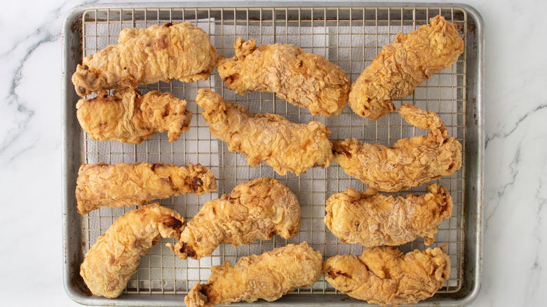 crispy fried chicken tenders on wire rack over lined baking sheet