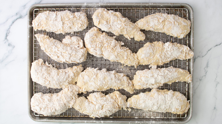 coated chicken tenders on wire rack over baking sheet
