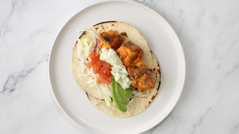 Buffalo chicken taco with avocado, tomato, and blue cheese dressing