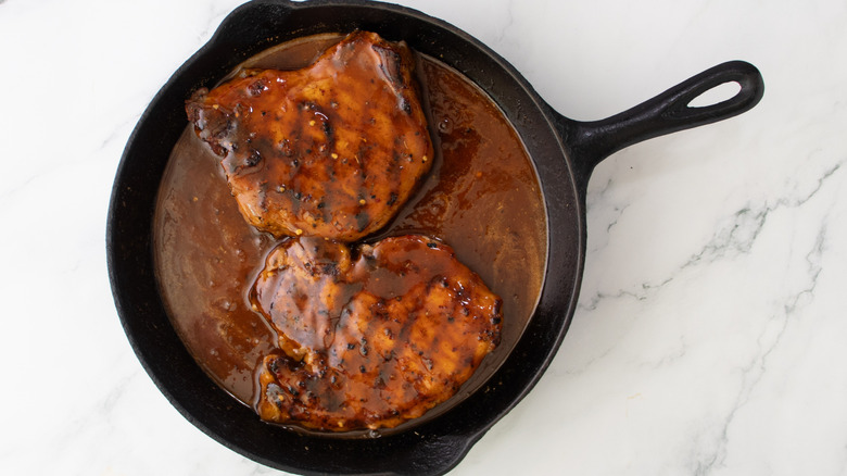 grilled pork chops in skillet with honey butter bbq sauce