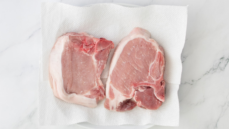 two pork chops on paper towel