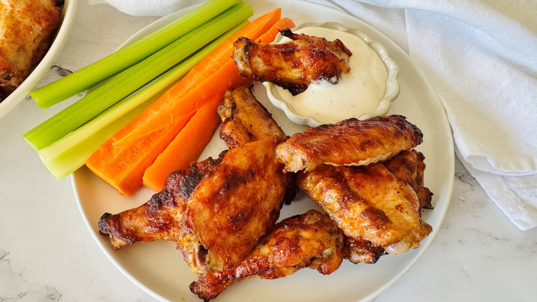 Chicken wings on plate with carrot and celery sticks and bowl of ranch