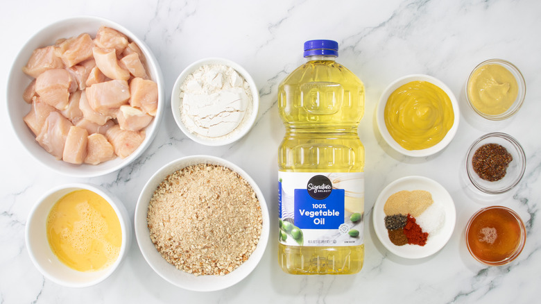 raw chicken with oil, flour, eggs, crumbs, and seasonings