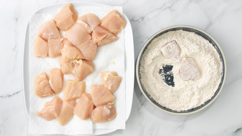 raw chicken chunks in a bowl of flour