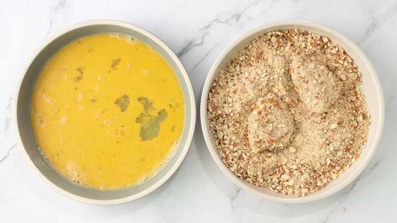 raw chicken chunks in a bowl of crumbs