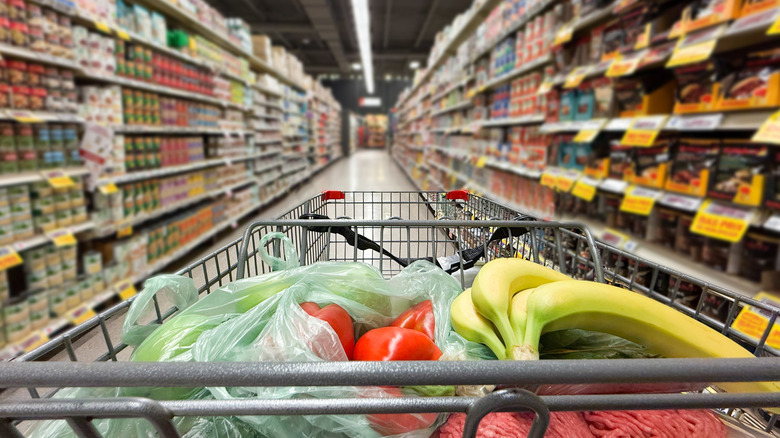 Close up of shopping cart in front of grocery aisle