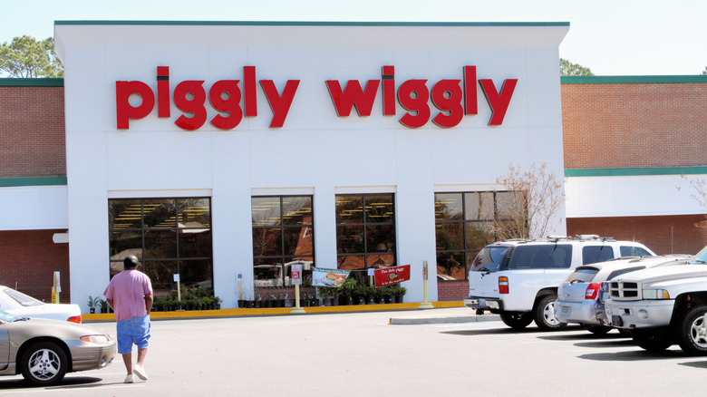 Customer walks through parking lot toward a Piggly Wiggly store entrance