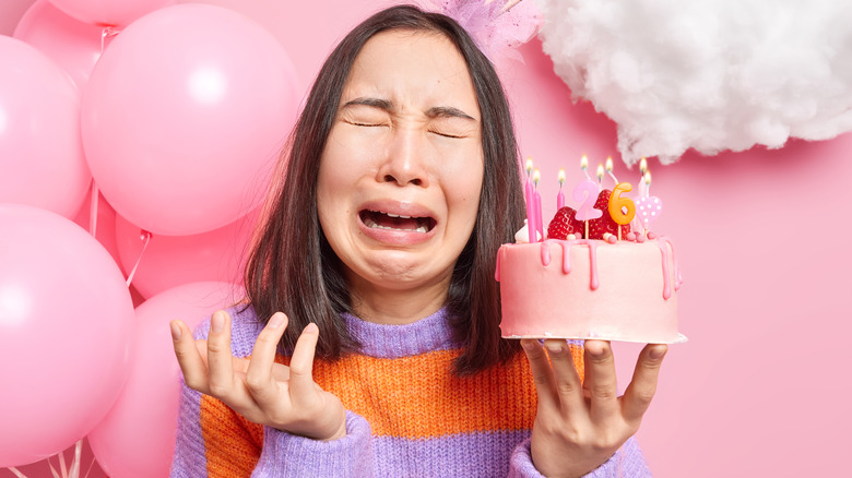 Woman crying with birthday cake