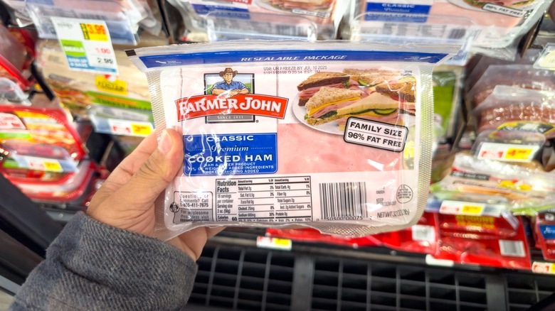 A hand holding up Farmer John classic cooked ham.