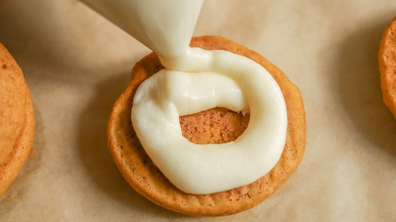 Piping frosting onto pumpkin whoopie pie