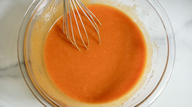 Liquidy pumpkin mixture in bowl with whisk