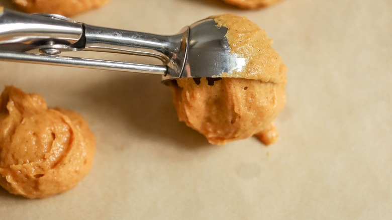 Scooping pumpkin whoopie pie batter onto baking sheet