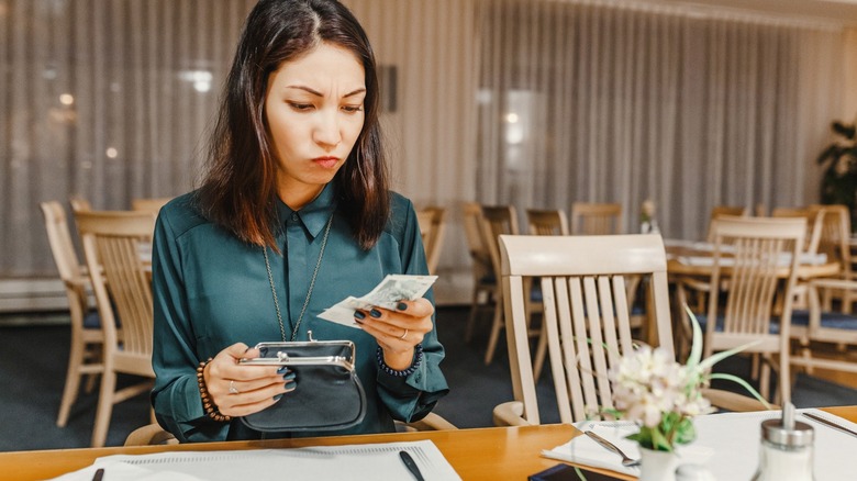 Woman frowns at expensive restaurant bill