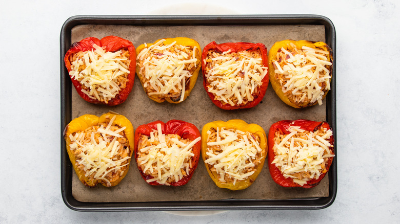 Cheesy stuffed bell peppers on parchment-lined baking sheet